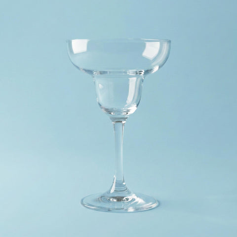 Clear glass cocktail glass on a light blue background