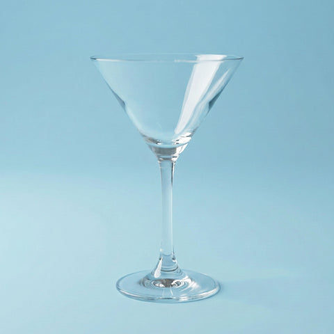 Clear martini glass on a light blue background