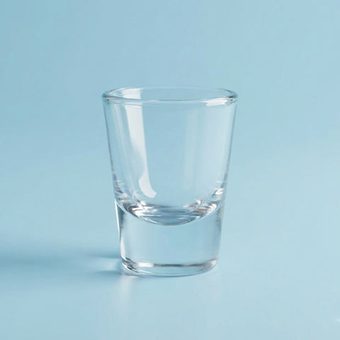 Clear glass shot glass on a light blue background